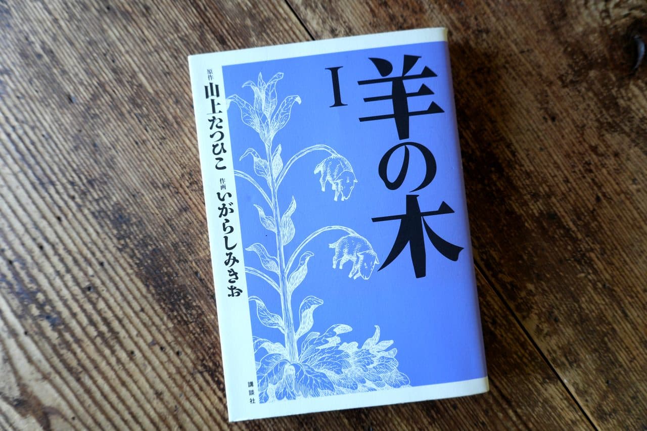山上たつひこ原作／いがらしみきお作画『羊の木』I（講談社）。青い地に、羊が実のようにぶら下がる植物が白線で描かれた表紙
